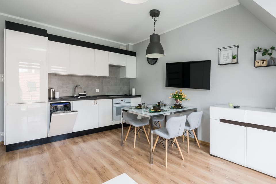 Fully equipped kitchen and dining area with a modern design, white cabinetry, and a small dining table.
