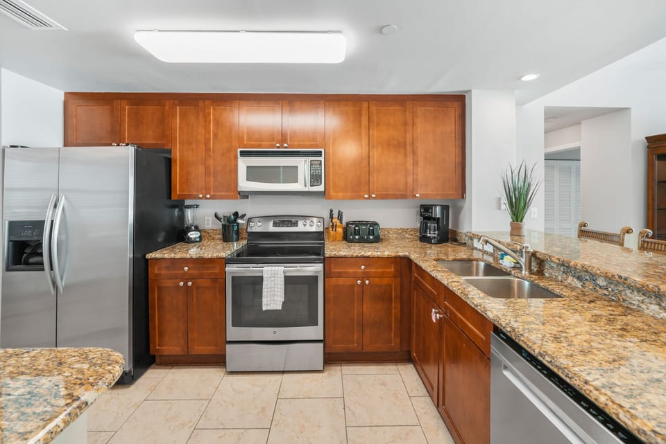 Your fully equipped kitchen awaits with granite counters, stainless appliances, and warm cherry cabinets—perfect for preparing meals.