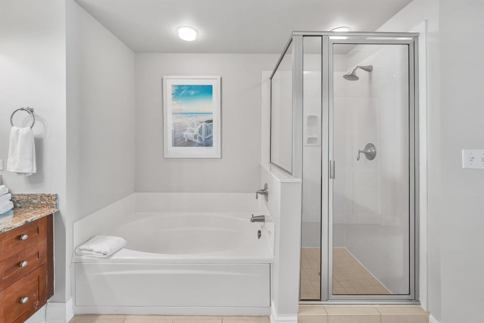 Unwind in your spacious bathroom featuring a soaking tub and glass-enclosed shower, perfect for relaxing after beach adventures.