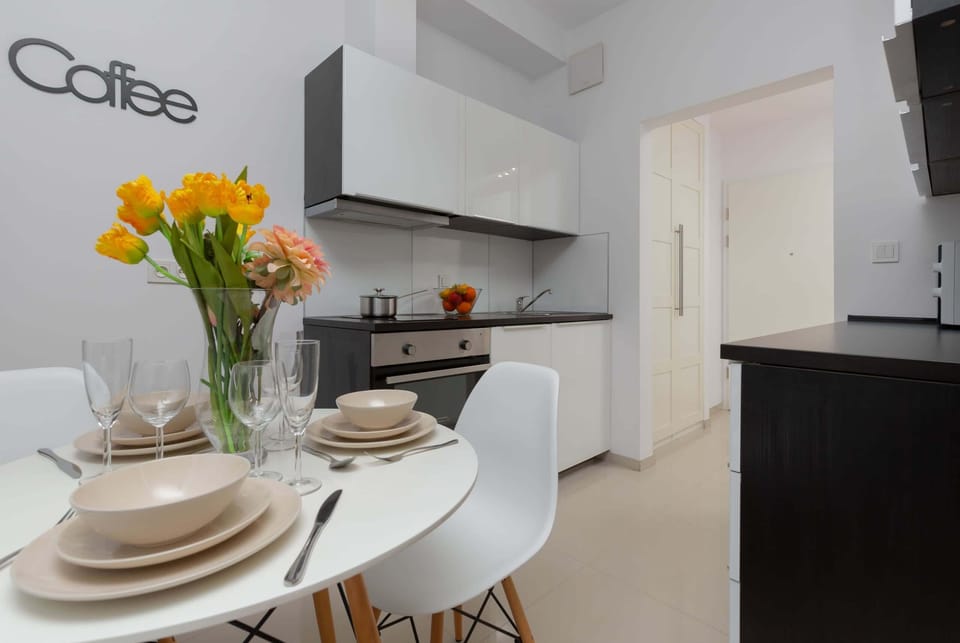 Kitchen and dining space with a white table, chairs, and fresh yellow flowers adding color.
