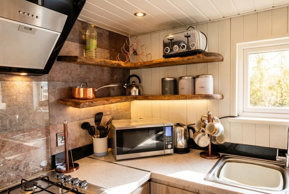 Fully equipped kitchen with copper touches, gas hob, oven, microwave and fridge.