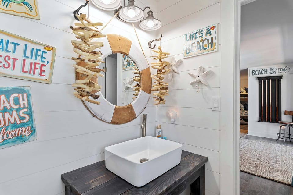 Bathroom w/ a sink, mirror, & nautical-inspired decor