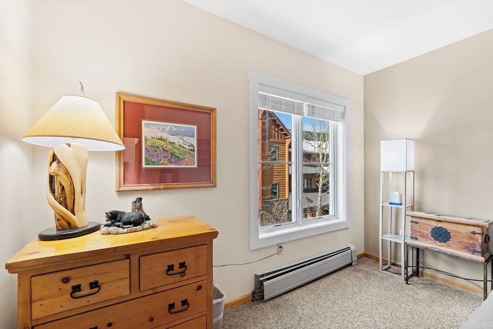 Cozy bedroom corner with rustic charm features warm wood furnishings and mountain views through your private window.