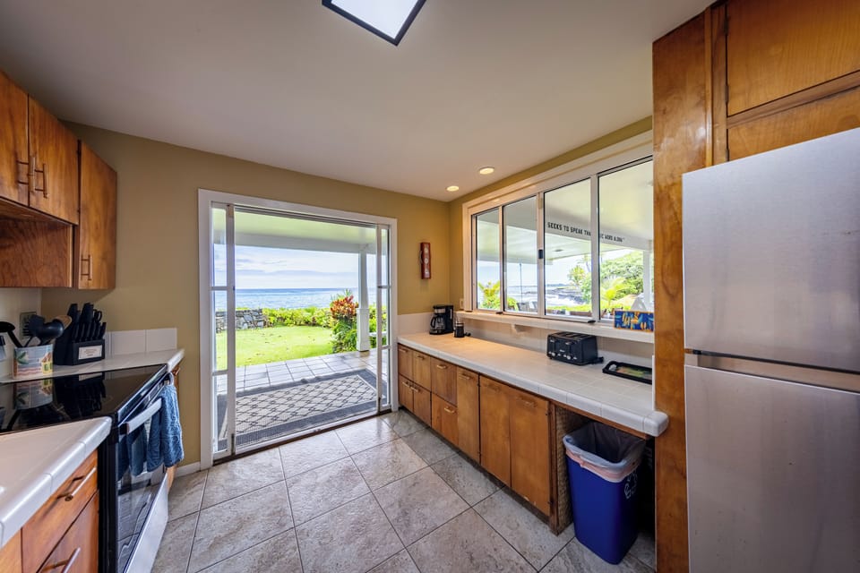 Bright galley kitchen with warm wood cabinets modern appliances and ocean views