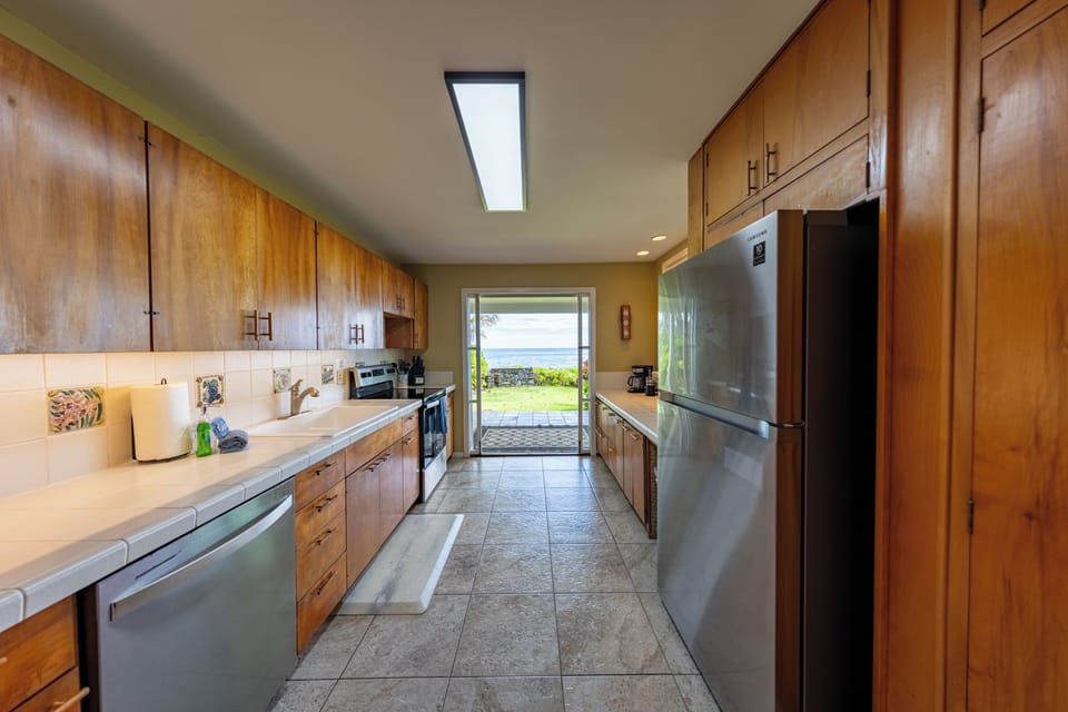 Bright galley kitchen with warm wood cabinets modern appliances and ocean views