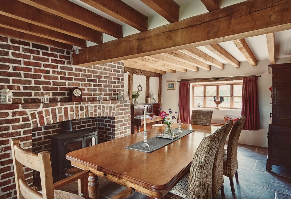 Traditional dining room with statement brick fireplace, games cupboard and piano