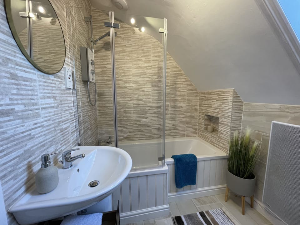 The bathroom comprises bath with overhead shower, WC, sink and heated towel rail