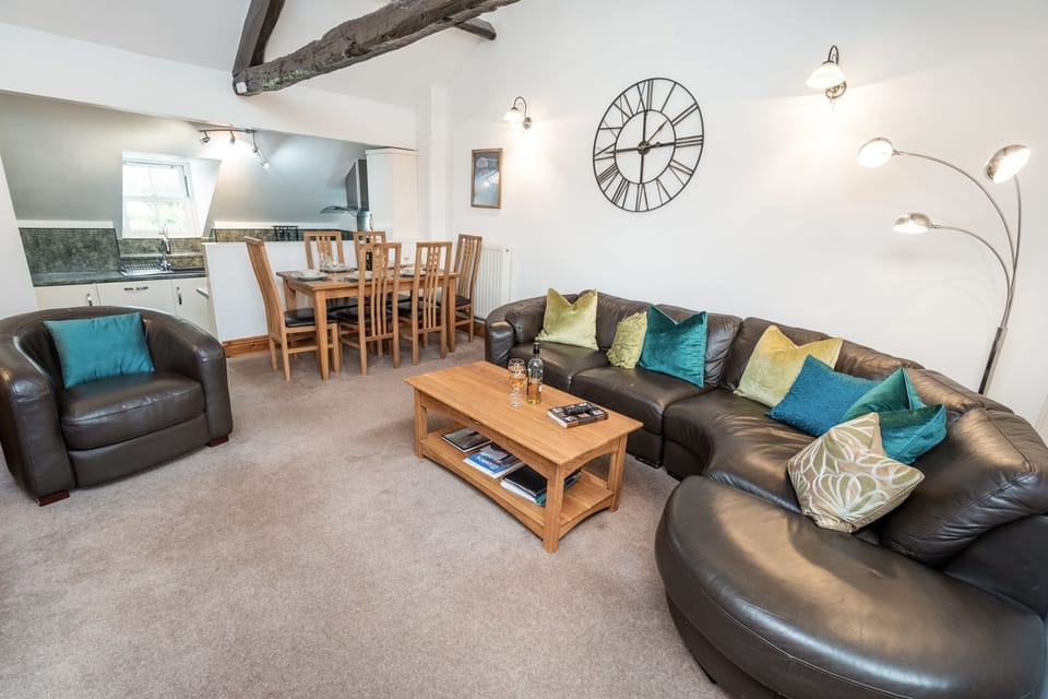 The living area features a large leather corner sofa and two armchairs