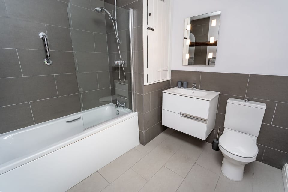 The modern bathroom is found on the 1st floor and features a bath with overhead shower