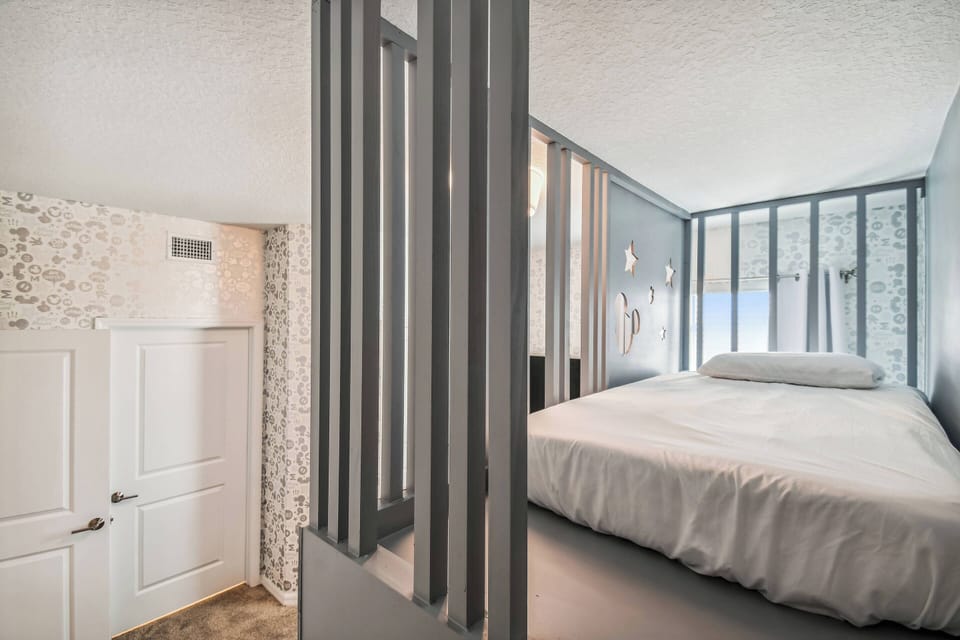Enjoy a cozy sleeping nook with a comfy bed framed by stylish wooden slats for privacy and an airy feel. The soft neutral tones and textured wall create a warm, tranquil atmosphere for a restful night.