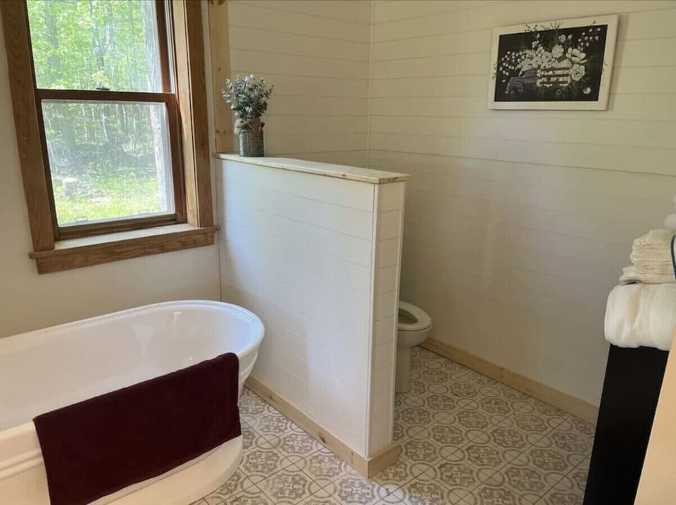 Primary Bathroom: Bright natural light, a vintage tub, and charming details await your relaxation!