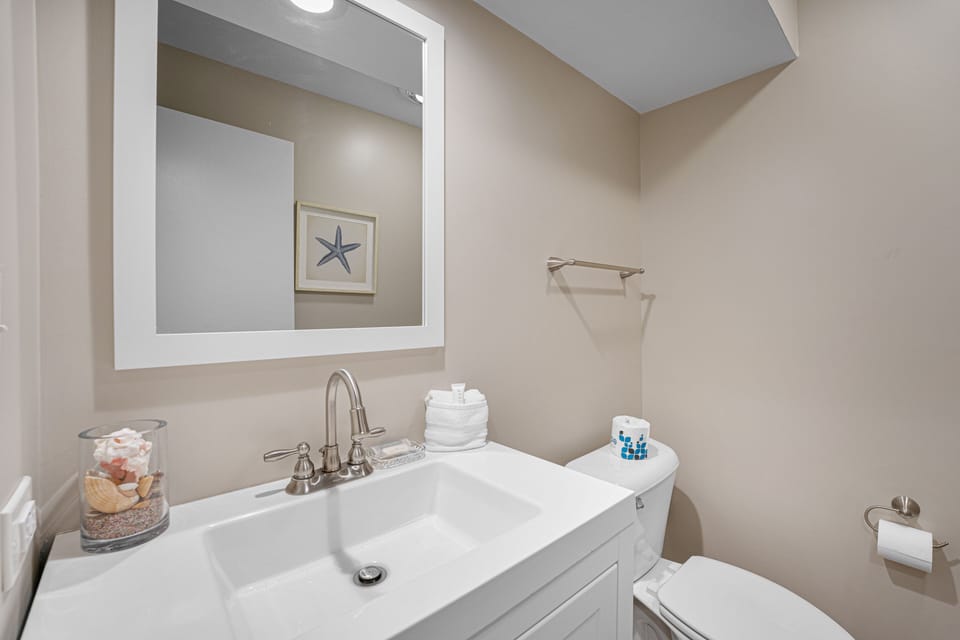 A bright and modern half bath featuring coastal-inspired décor, sleek fixtures, and clean lines