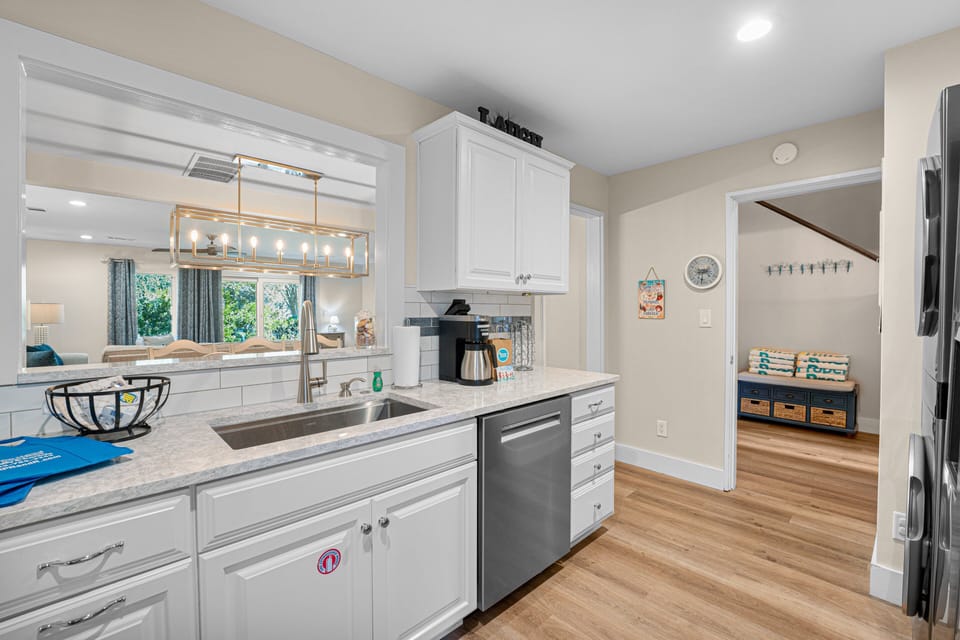 A bright and welcoming kitchen with quartz countertops, stainless-steel appliances, and a pass-through window that opens to the dining area
