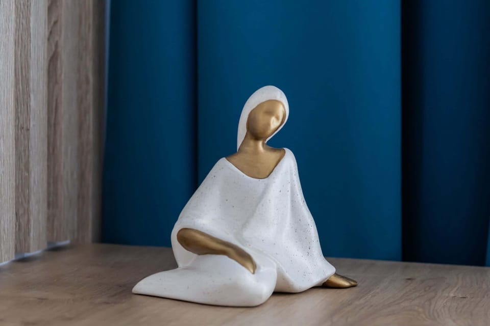 Decorative details featuring a white figurine against a deep blue curtain.
