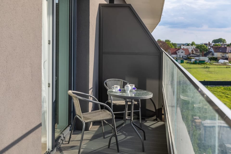 Balcony with a small table and chairs overlooking a green and peaceful view.
