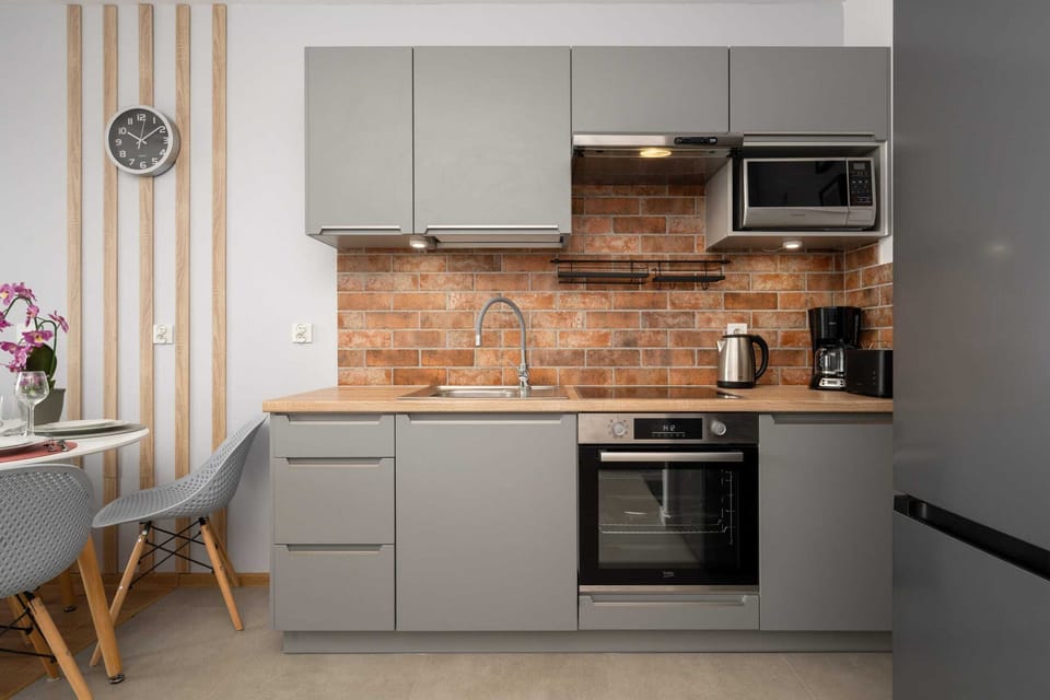 Functional kitchen with gray cabinets and a brick backsplash for a rustic touch.
