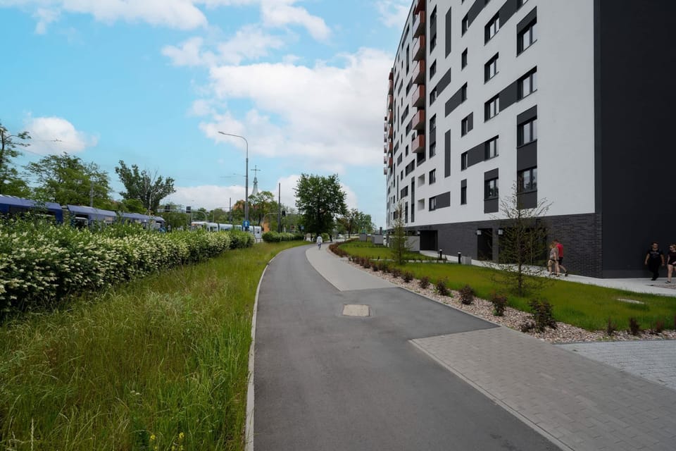 Exterior view of the residential building with green spaces and walking paths.
