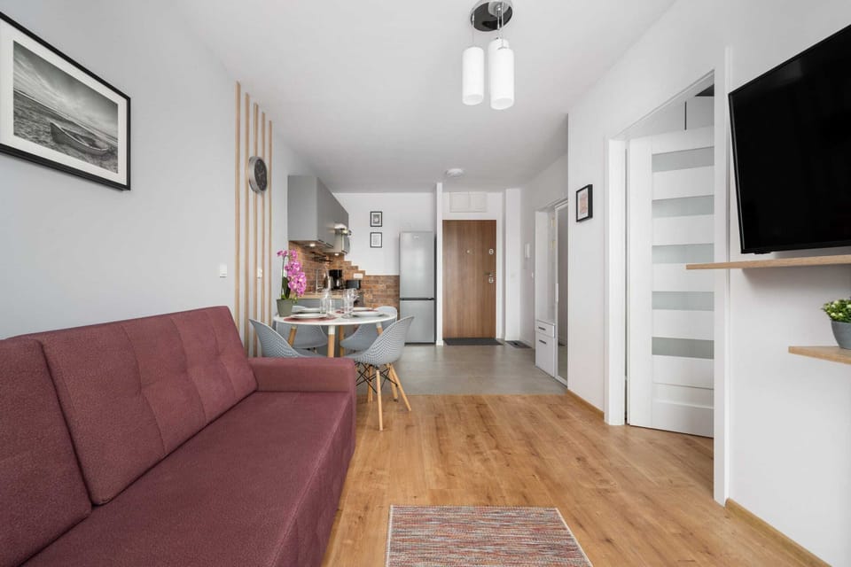 Bright and cozy living area with a pink sofa, dining table, and wall art accents.
