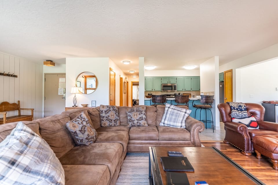 Spacious living area with large mounted flat screen TV, hardwood flooring, access to the private balcony, wood burning fireplace and ample seating.