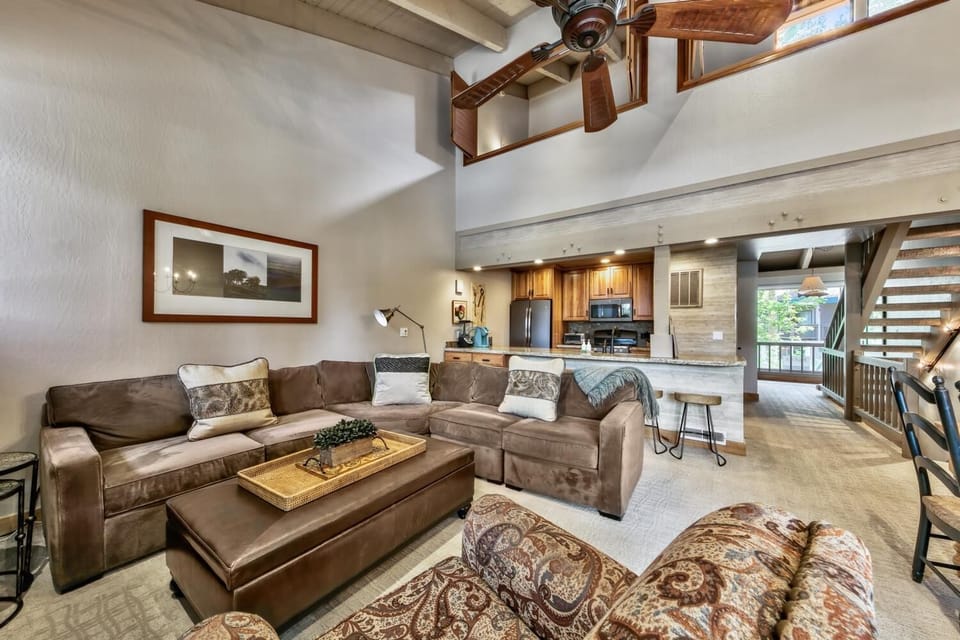 Relax in your spacious living area with plush leather seating, soaring ceilings, and an open-concept design that flows into the modern kitchen.
