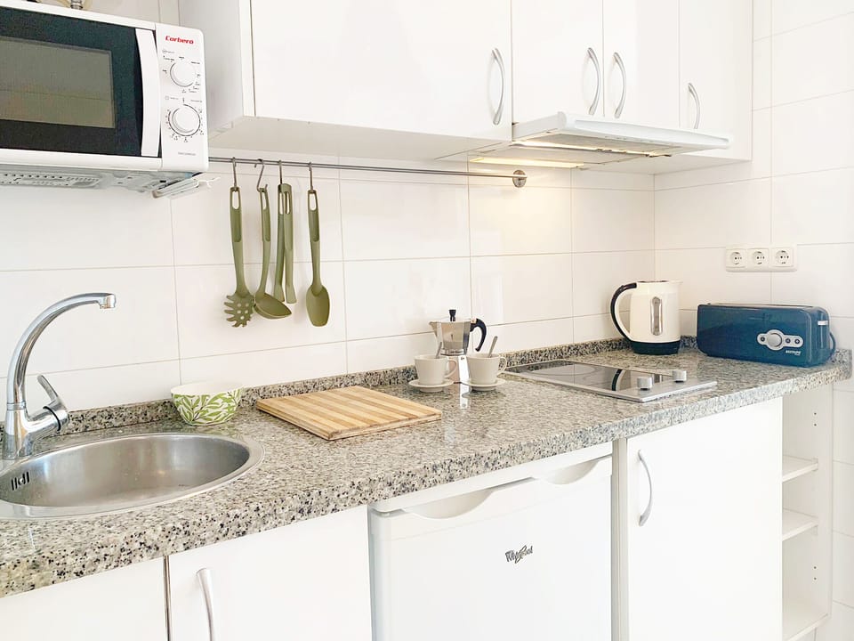 Comfortable kitchen, equipped with a refrigerator, stove, microwave, and storage.