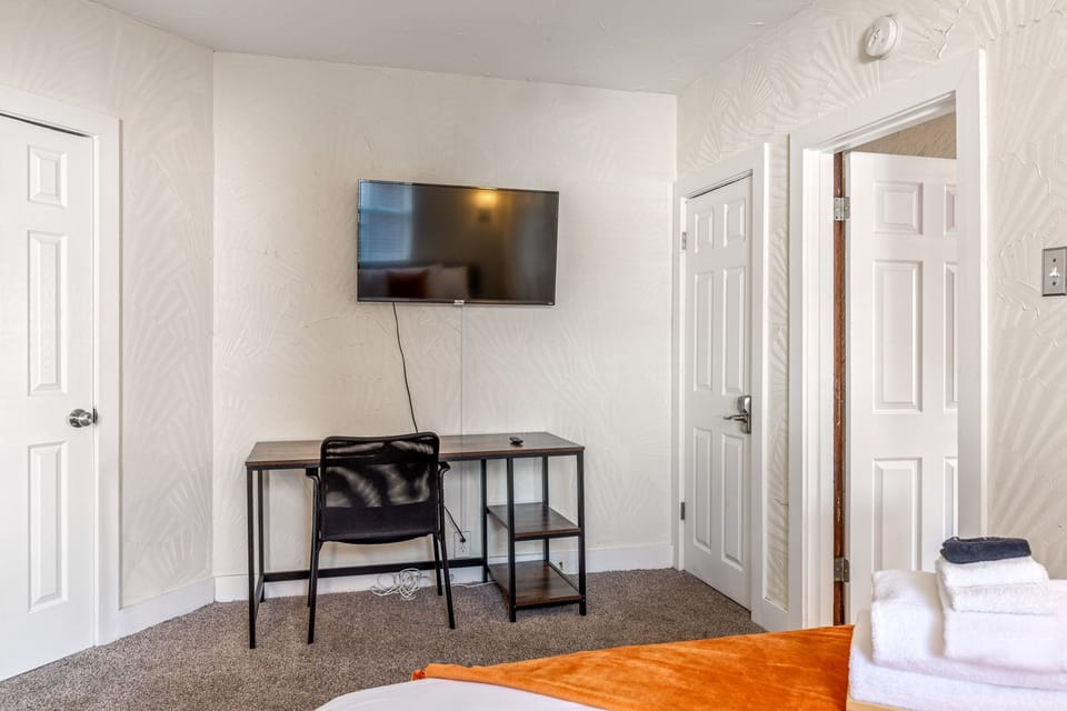 Bedroom with a wall-mounted TV and compact work desk beside the bed.