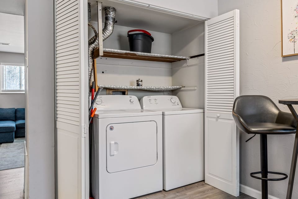 Side-by-side laundry appliances inside a louvered utility closet.