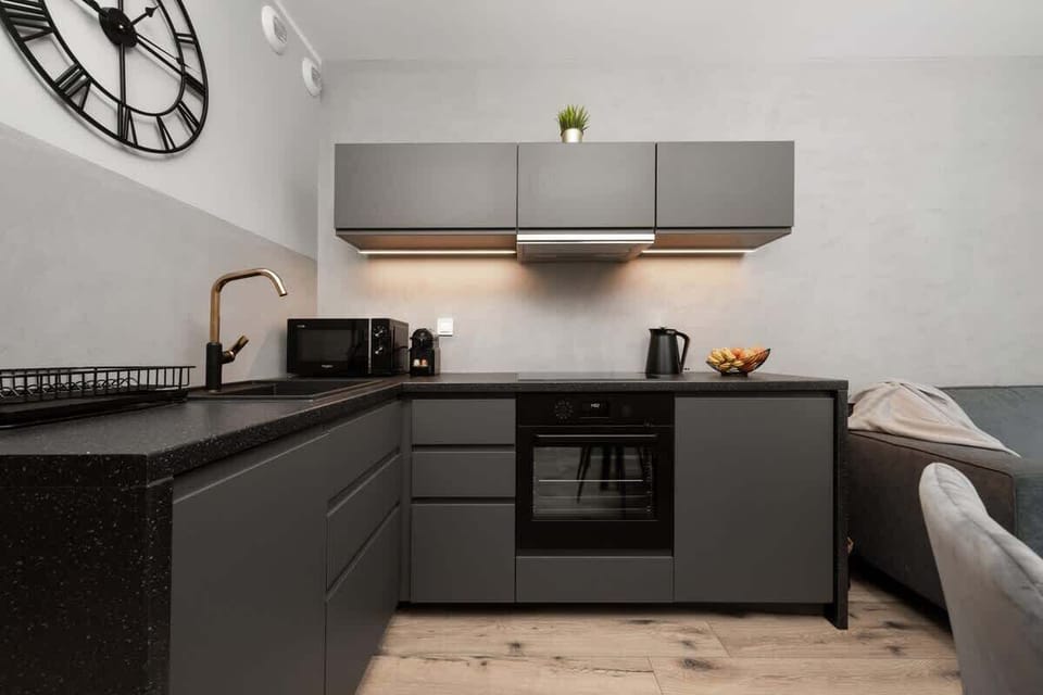 Modern kitchen with dark cabinets, built-in appliances, and bright lighting.
