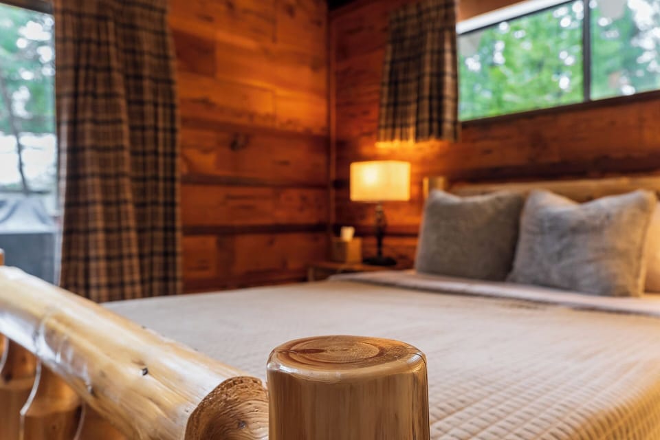 Bedroom 1: Drift off in a log-frame bed wrapped in forest views.