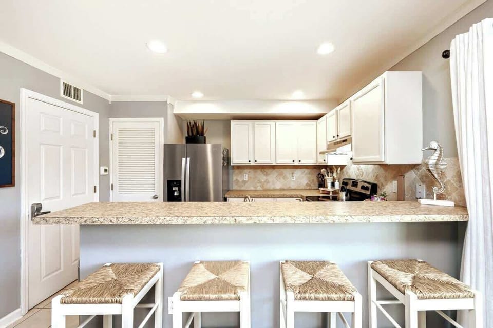 There is a breakfast bar with four barstools to gather and enjoy meals together.