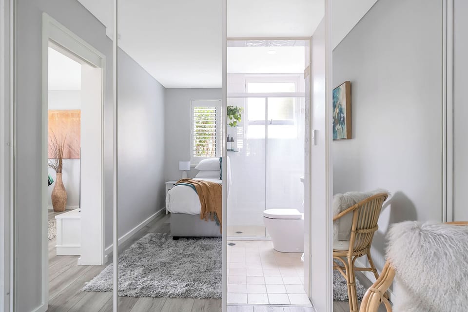 Ensuite bathroom is hidden behind mirrored wardrobe doors
