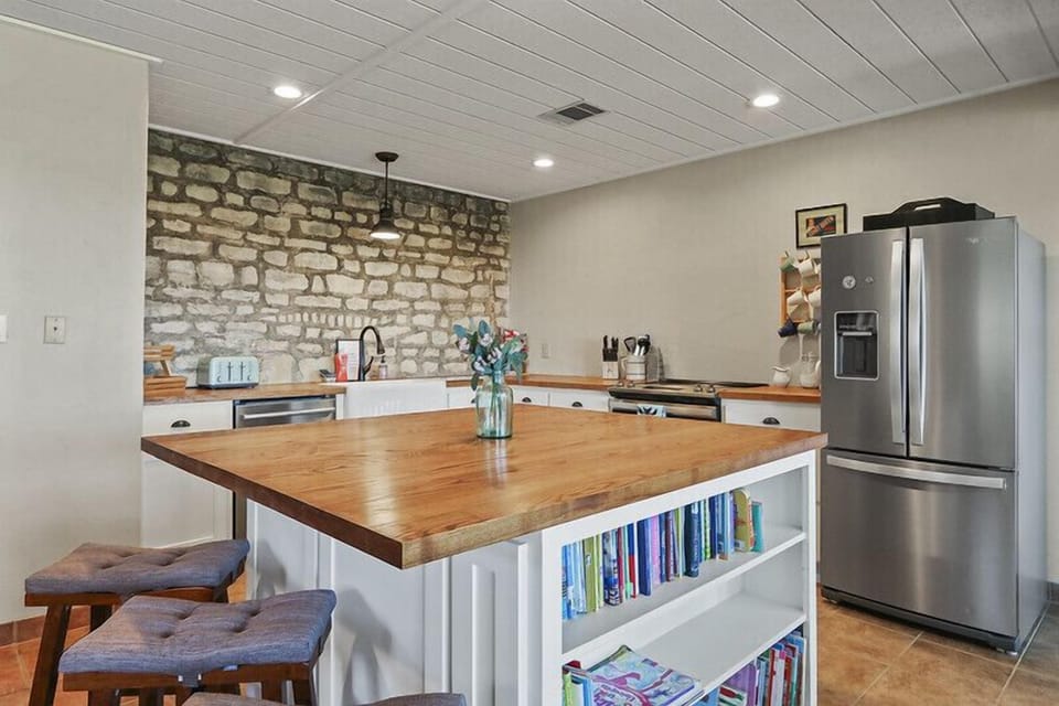 Closer view of kitchen bar with seating.  The modern stainless steel appliances in the kitchen can also be seen.