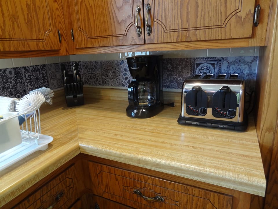 Kitchen with dining table, dishwasher, stove, fridge, microwave, Keurig and regular coffee pot, lots of cupboard space, dishes, pots, pans, silverware.