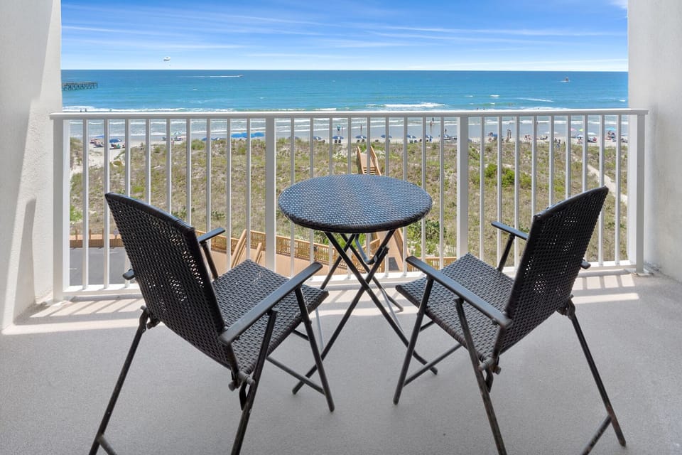 Oceanfront balcony with two chairs and a small table at Carolina Dunes 403, a 2-bedroom Cherry Grove condo rental