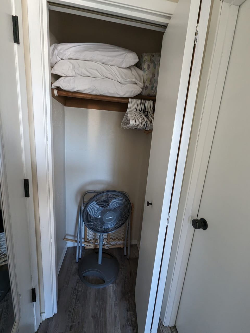 Bedroom closet has luggage rack, portable fan, baby gate, extra pillows & blanke