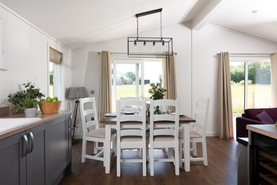 A dining table and chairs for all guests to eat together or play games - Forget Me Not Lodge