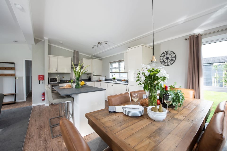 A dining table with seating for all guests and the kitchen - Daisy Lodge