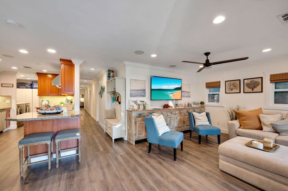 Bright and spacious living room with comfortable seating, shows the hallway to the bedroom