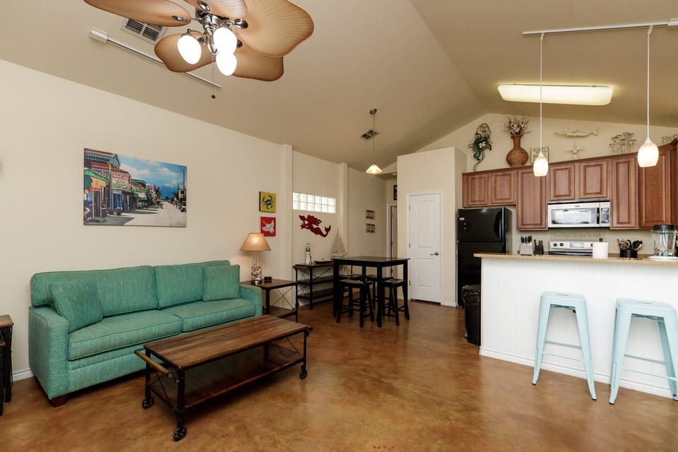 Relax in your open-concept living space where coastal-inspired decor meets modern comfort, complete with a fully equipped kitchen and cozy seating area.