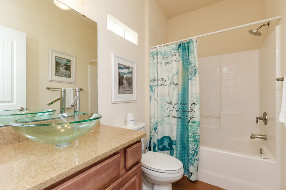 Refresh in your stylish bathroom featuring a unique glass vessel sink, warm granite counters, and coastal-themed decor that creates a spa-like retreat.