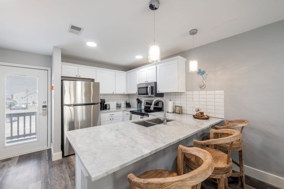 Gather around your modern kitchen island with stylish pendant lighting, stainless steel appliances, and marble countertops.