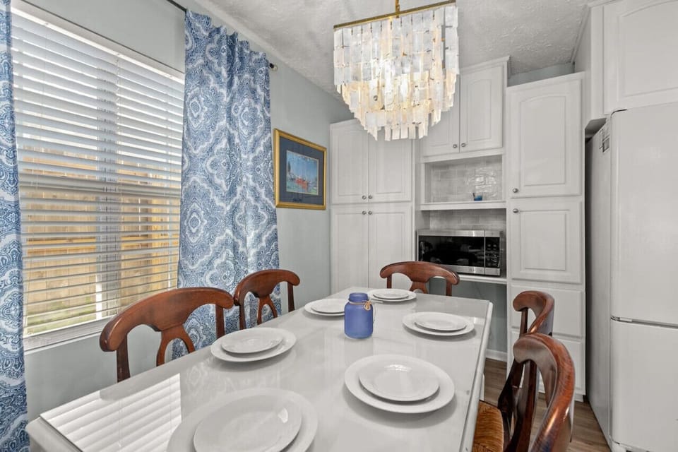 `Dining table beautifully illuminated by a charming chandelier.