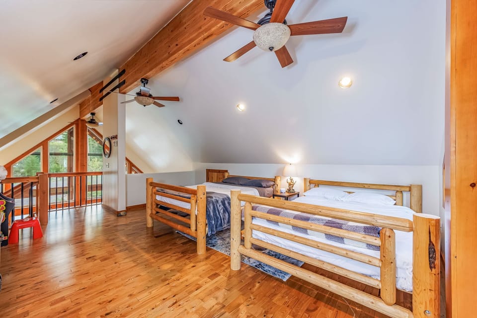 Upstairs loft bedroom with two queen size beds, roller bed, a sink, and amazing views