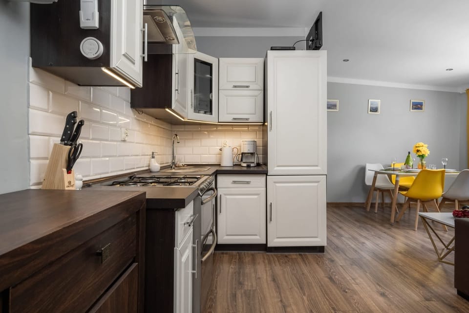  A modern kitchen with white cabinets and wooden accents. The space includes a stove, oven, and countertop appliances.