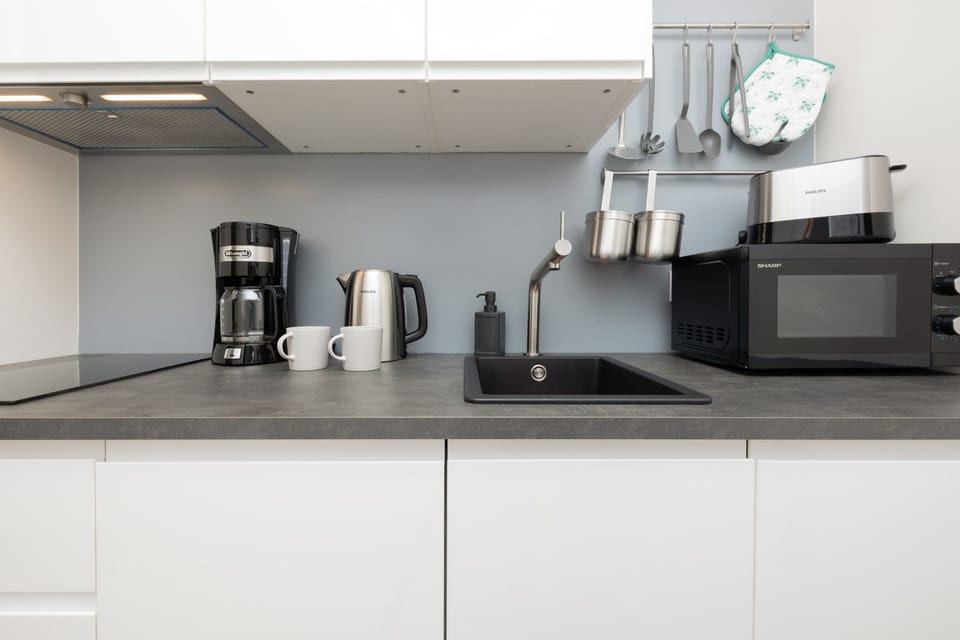 A kitchen showing hanging utensils, such as spatulas, an oven mitt, and a ladle.