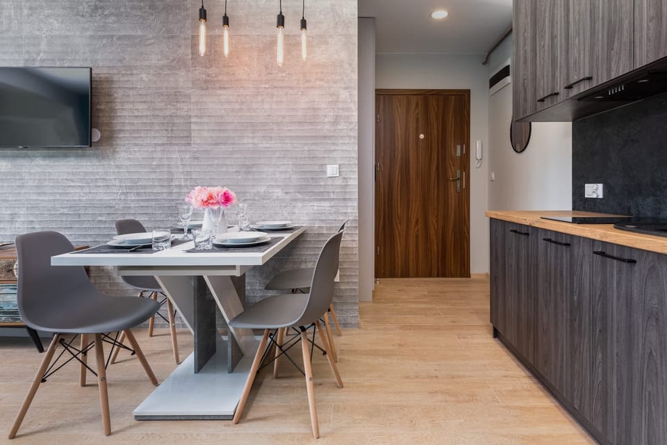 A dining area with a turquoise accent wall and a sleek modern dining table. The chairs are black and white, giving a modern touch.