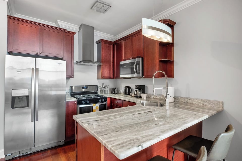 Fully equipped kitchen with modern cherry wood cabinetry, granite countertops, and stainless steel appliances.