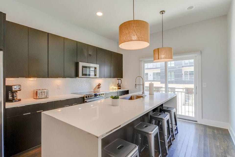 Sleek modern kitchen with dark cabinetry, an island, and stylish pendant lighting