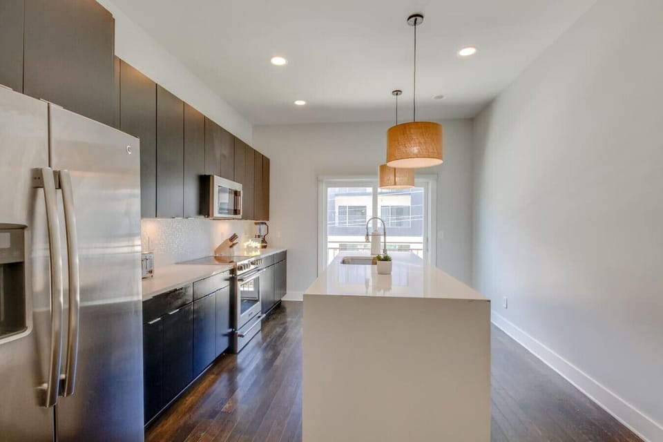 Contemporary kitchen with dark cabinetry, a center island, and warm pendant lights