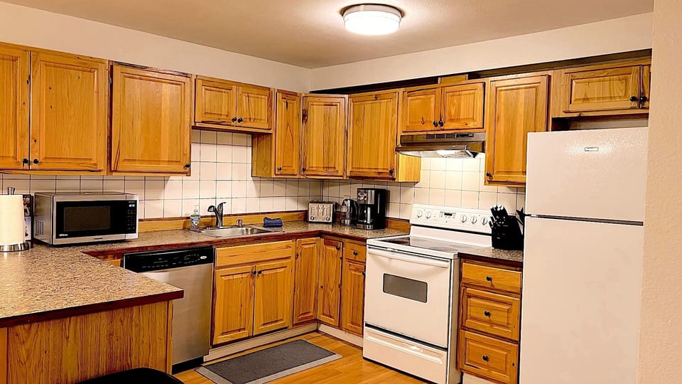 Large full kitchen with coffee pot, toaster, microwave, knife block, and plenty of dishes and cooking supplies.